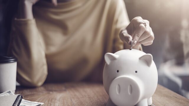 Woman putting coin in piggy bank - small
